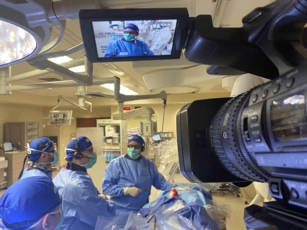 High-end medische beeldregistratie Close-up van een professionele videocamera gericht op chirurgen, met live weergave van de operatie op een monitor.